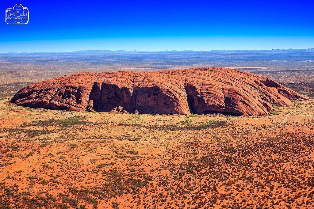 Uluru, or Ayers Rock, emerges from the Earth in stark contrast to its flat surroundings.