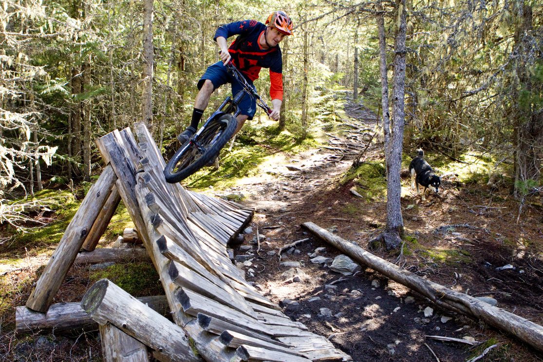 Riding a wooden feature on a Whistler cross country bike trail.