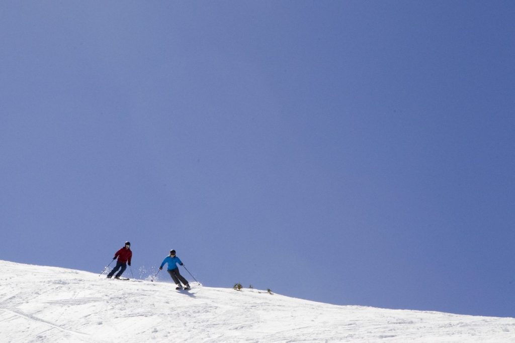 Two skiers enjoying a perfect blue bird day on the slopes.