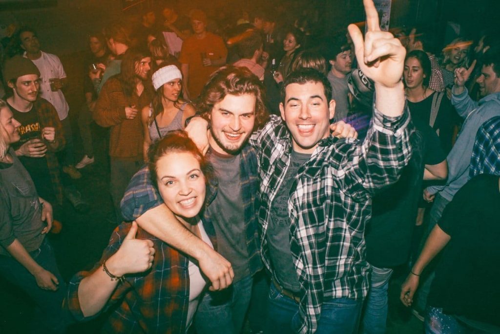 A chick, dude and bro in flannel shirts on the dance floor.