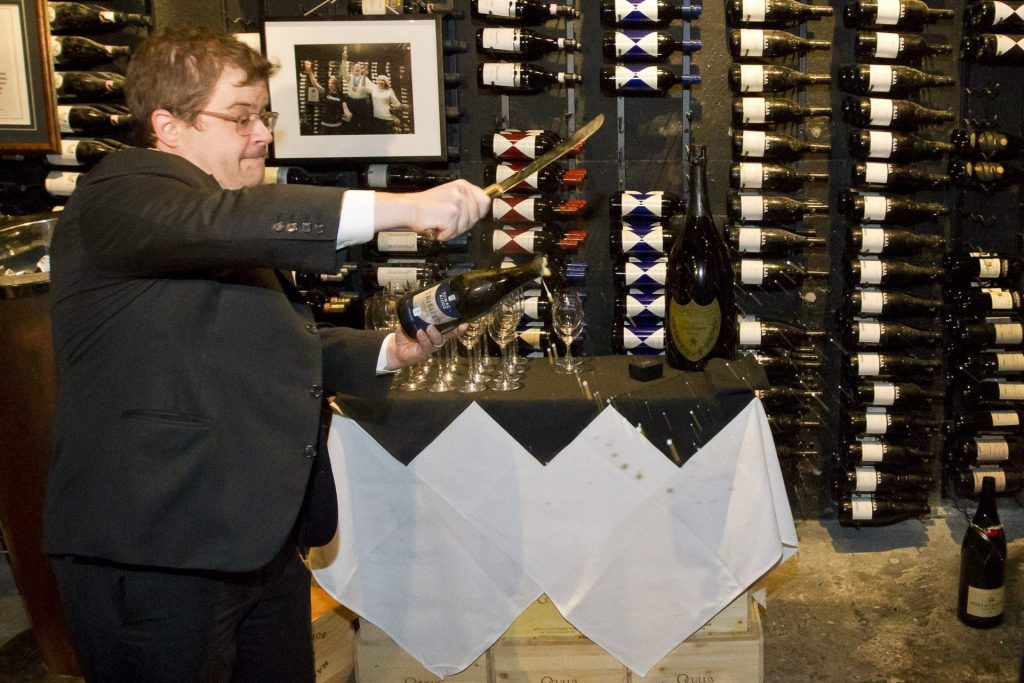 Patton Oswalt sabres a champagne bottle. Image: Joern Rohde