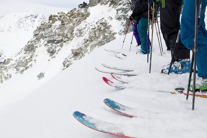 Skiers lined up at the top of a slope.