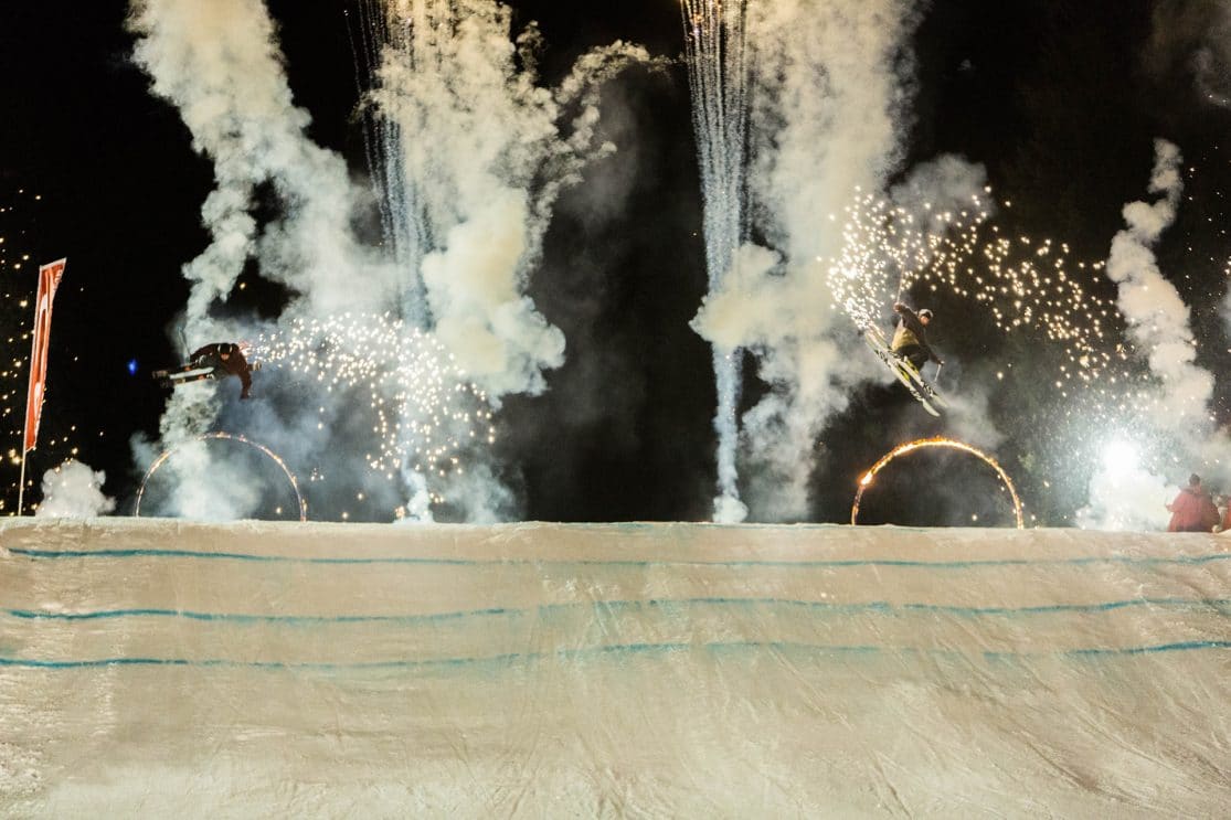 Skiers sending it against a background of fireworks.