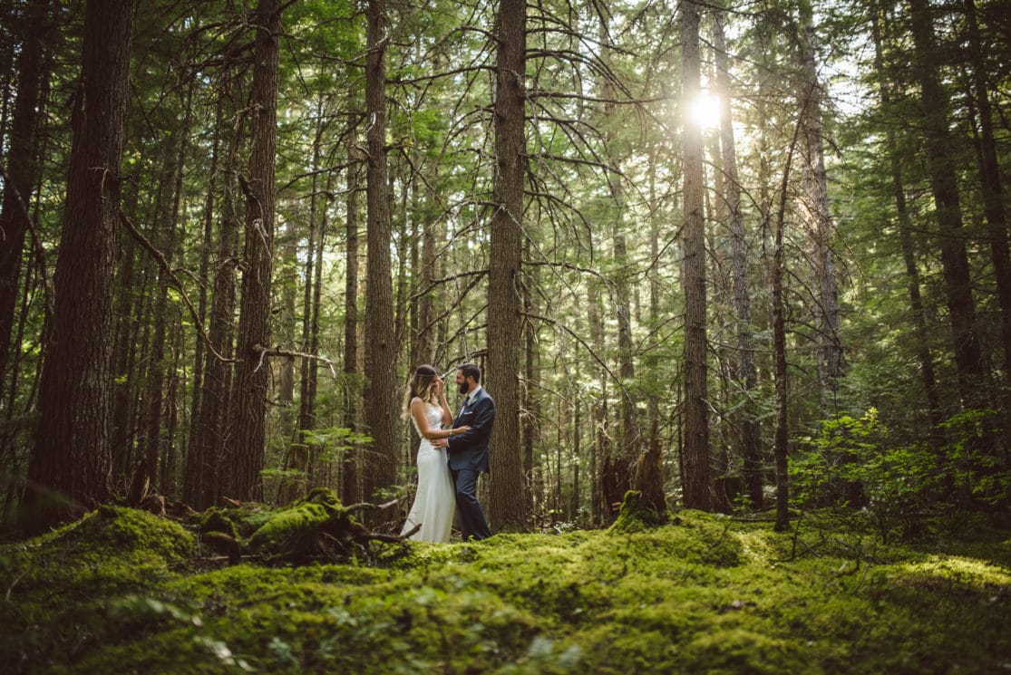 A bride and groom in the lush, green Whistler forest.